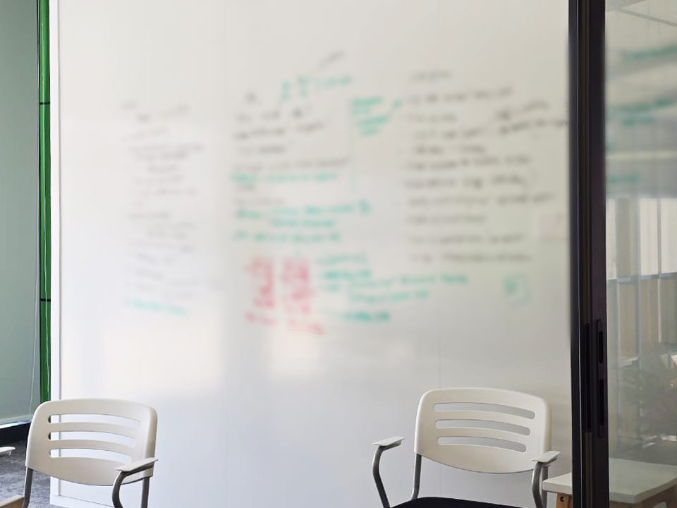 Ceramic Steel whiteboard wall covered in meeting notes in a glass-walled meeting room