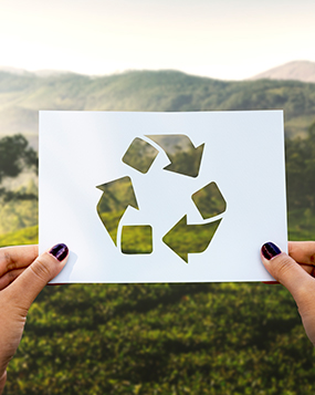Hands holding a recycling symbol cut from paper