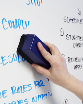 A hand wiping a whiteboard clean with an eraser
